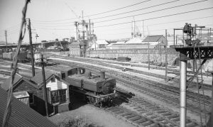 3. Dock St 1963 In this view from Octopus Bridge, the Dock Street pilot, 0-6-0 PT No. 1656, waits outside the Dock St Goods Yard ground frame, sited at the entrance to the yard. The photograph is undated but, in the background, the erection stage of George Street Bridge confirms that it is sometime during 1963. East Dock St signal box, in the distance, and other boxes in the immediate area closed on 25 January 1960, all lines then being controlled by a new Dock St box sited just out of picture to the right. M.R.S Collectio