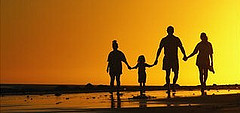 Image of family holding hands towards sunset